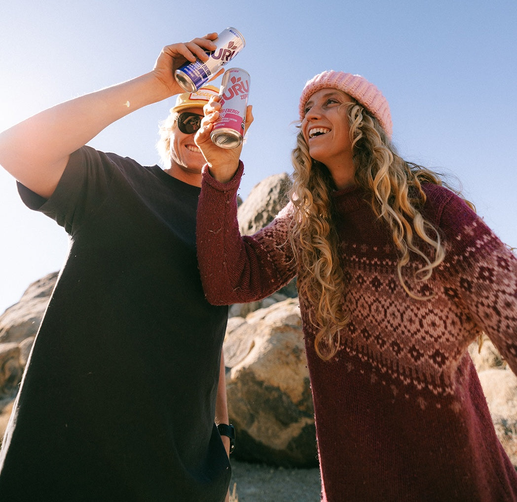 Two models pose smiling as they cheers their Guru Energy cans.