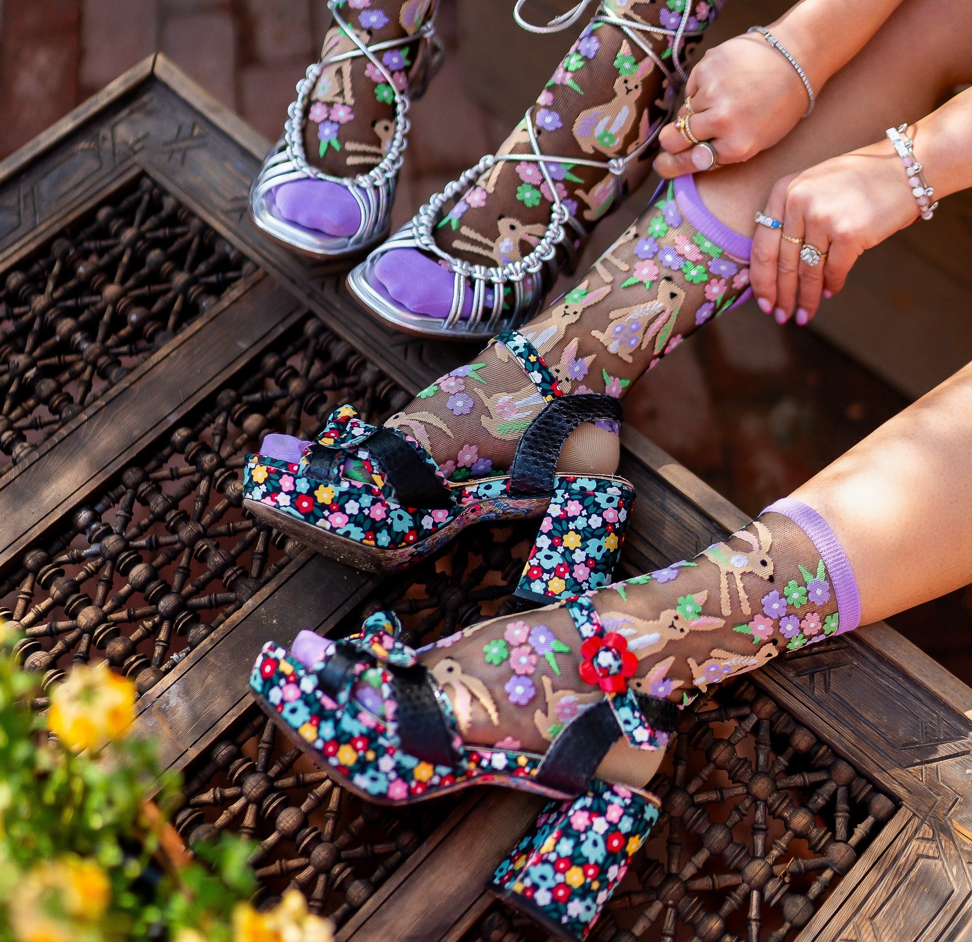Two models wearing Sock Candy Rabbit Floral black sheer socks and heels.