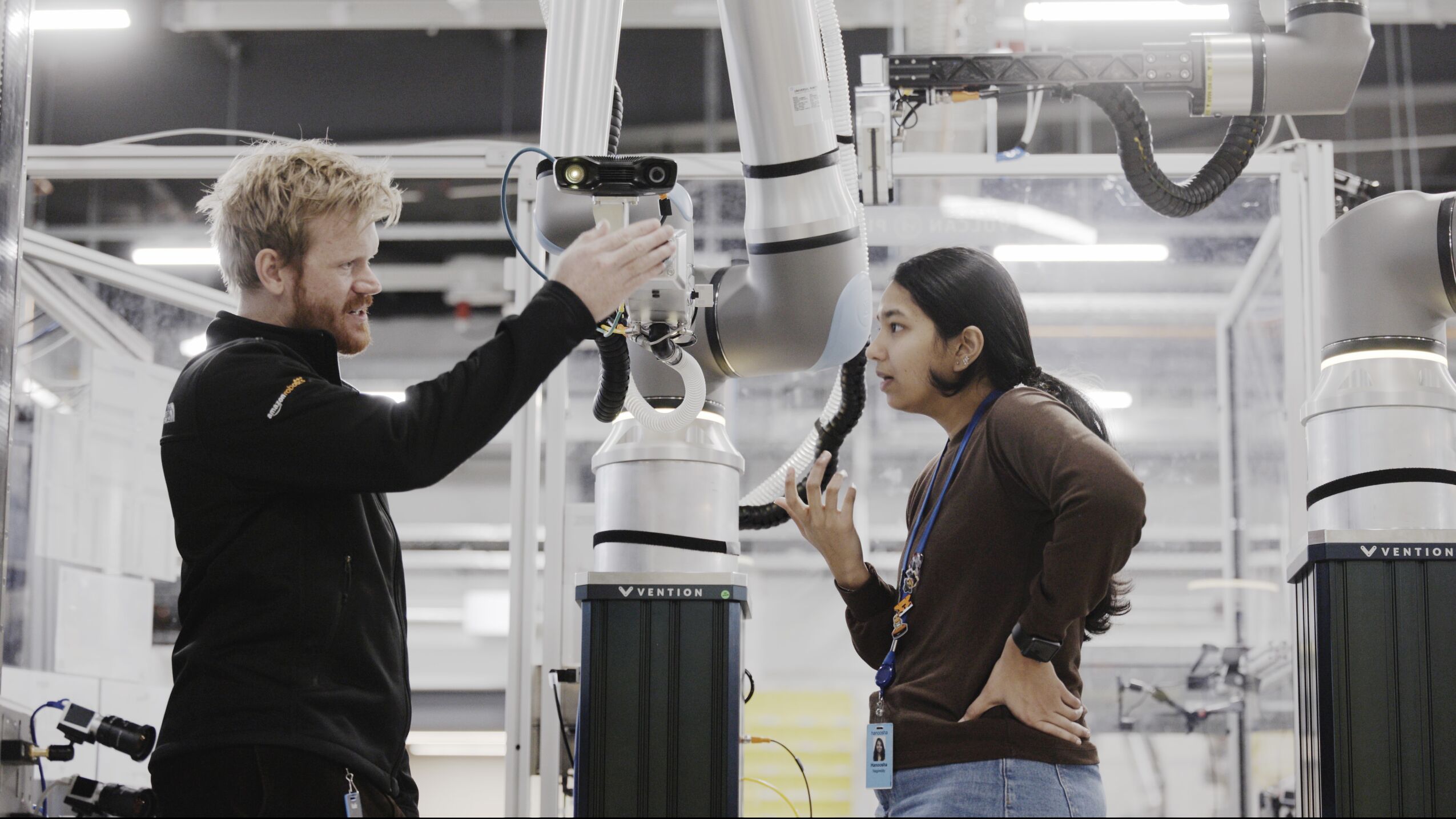 Two Amazon employees with Amazon's Vulcan robot