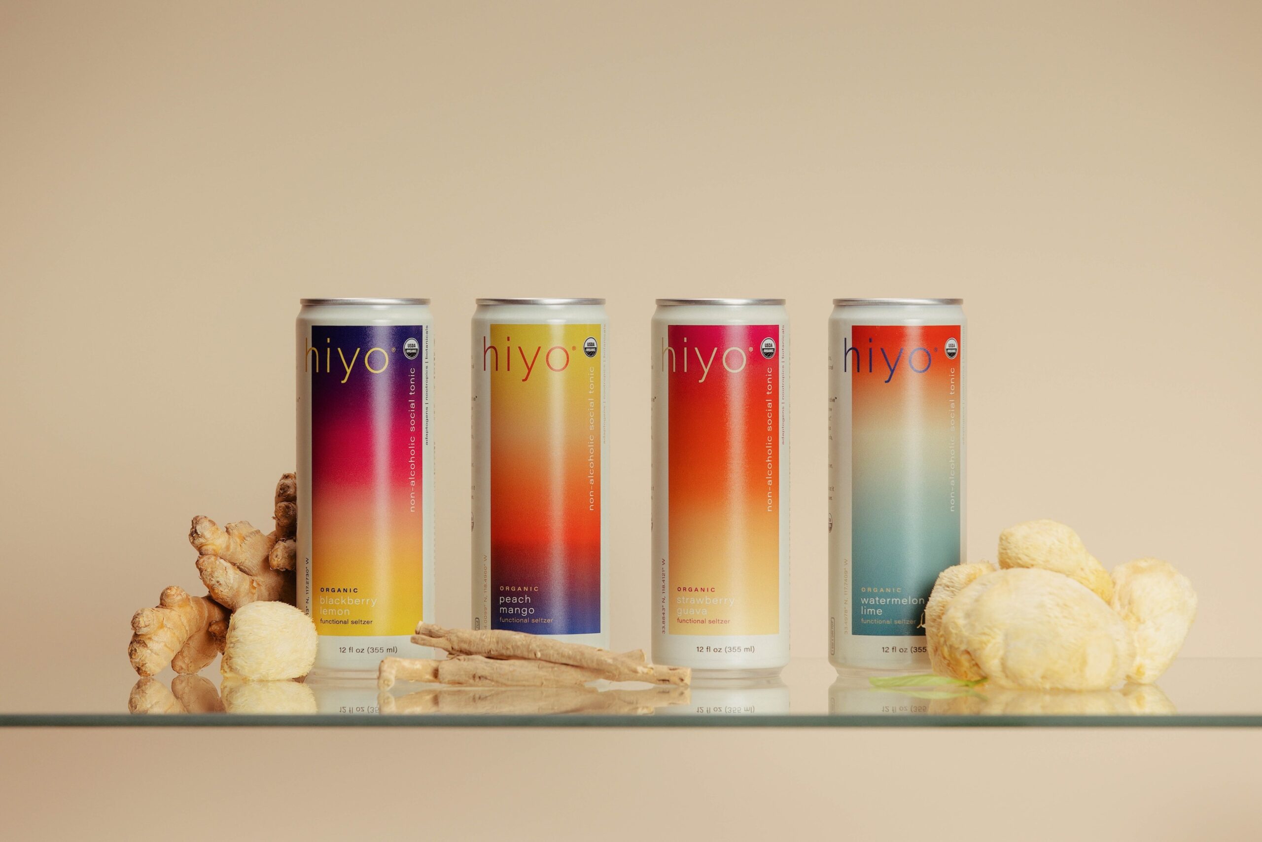 Hiyo cans pictured from left to right, blackberry lemon, peach mango, strawberry guava, and watermelon lime with the functional ingredients laid out next to them.