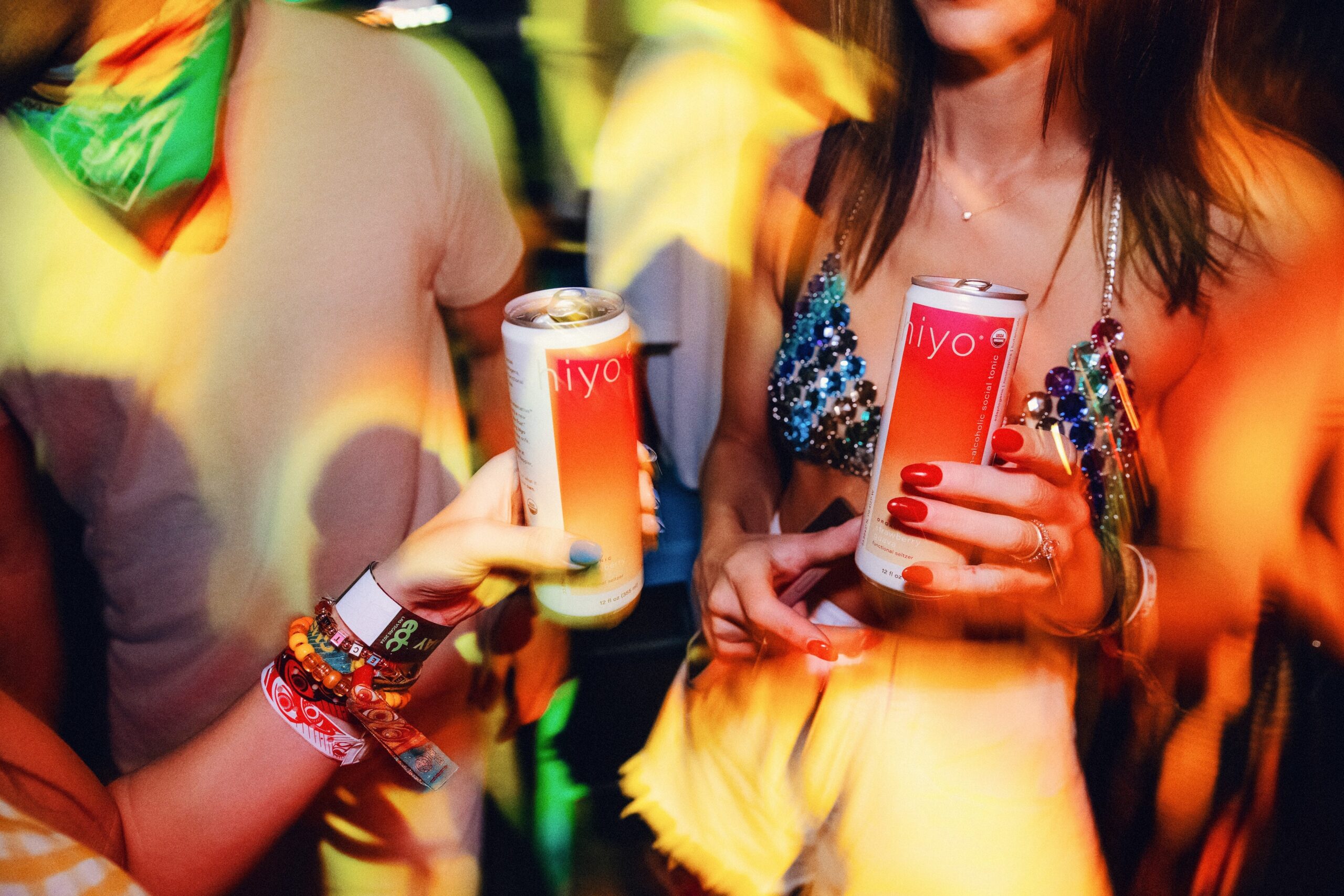 Two hands holding Strawberry Guava Hiyo cans at a concert, about to cheers.