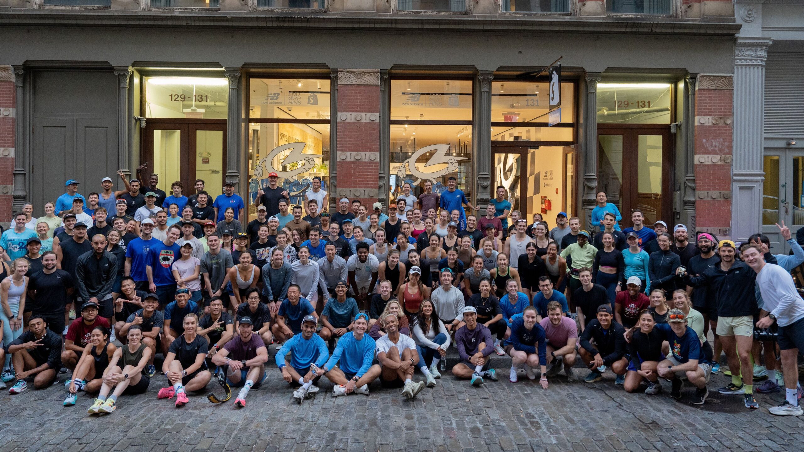 A group of runners in predominantly blue running gear from the Endorphins community pose for a photo outside of Shopify New York. The Shopify New York storefront features bricks and historical New York architecture.The Endorphins community gathered at Shopify New York to connect, train, and celebrate at a special pop-up over the New York Marathon weekend in 2024