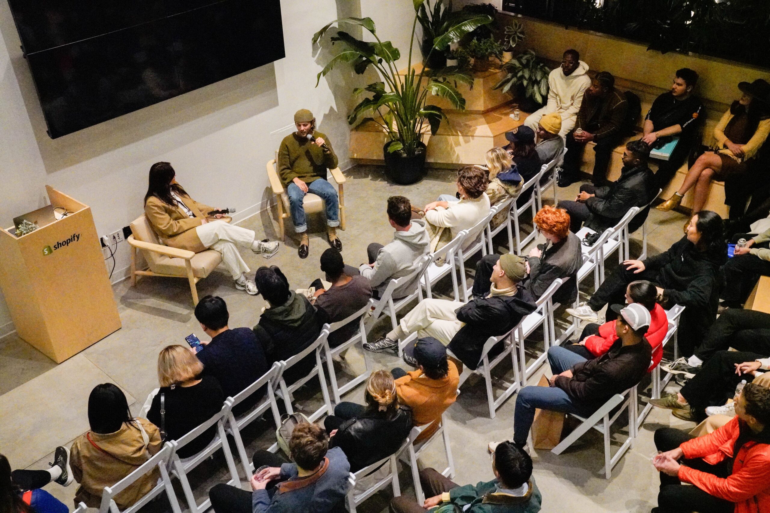 A group of runners are seated on white chairs, facing a black screen, as they listen to Ardith Singh, Bandit’s co-founder and lead designer.