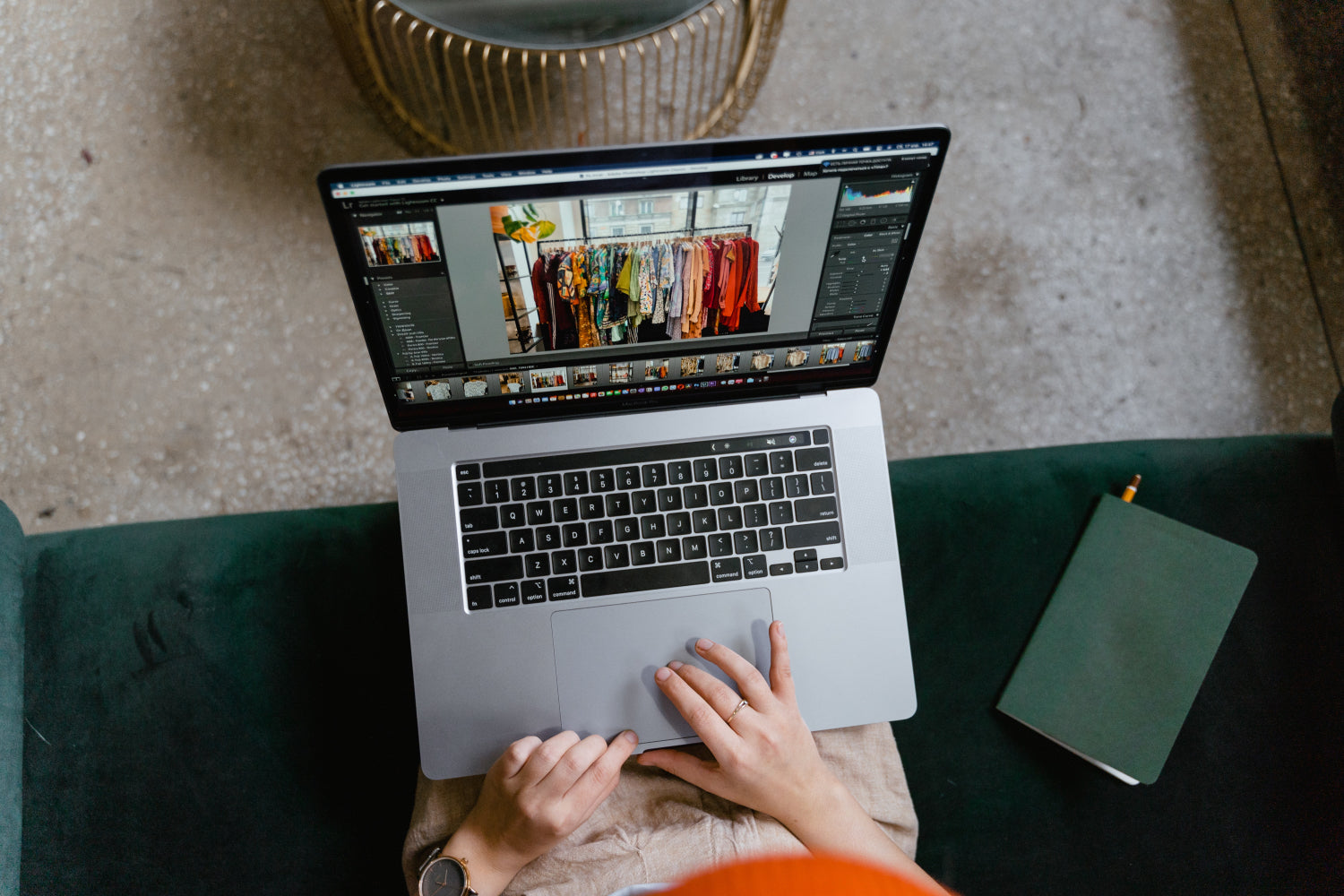 A person types on a laptop while editing photos of clothing
