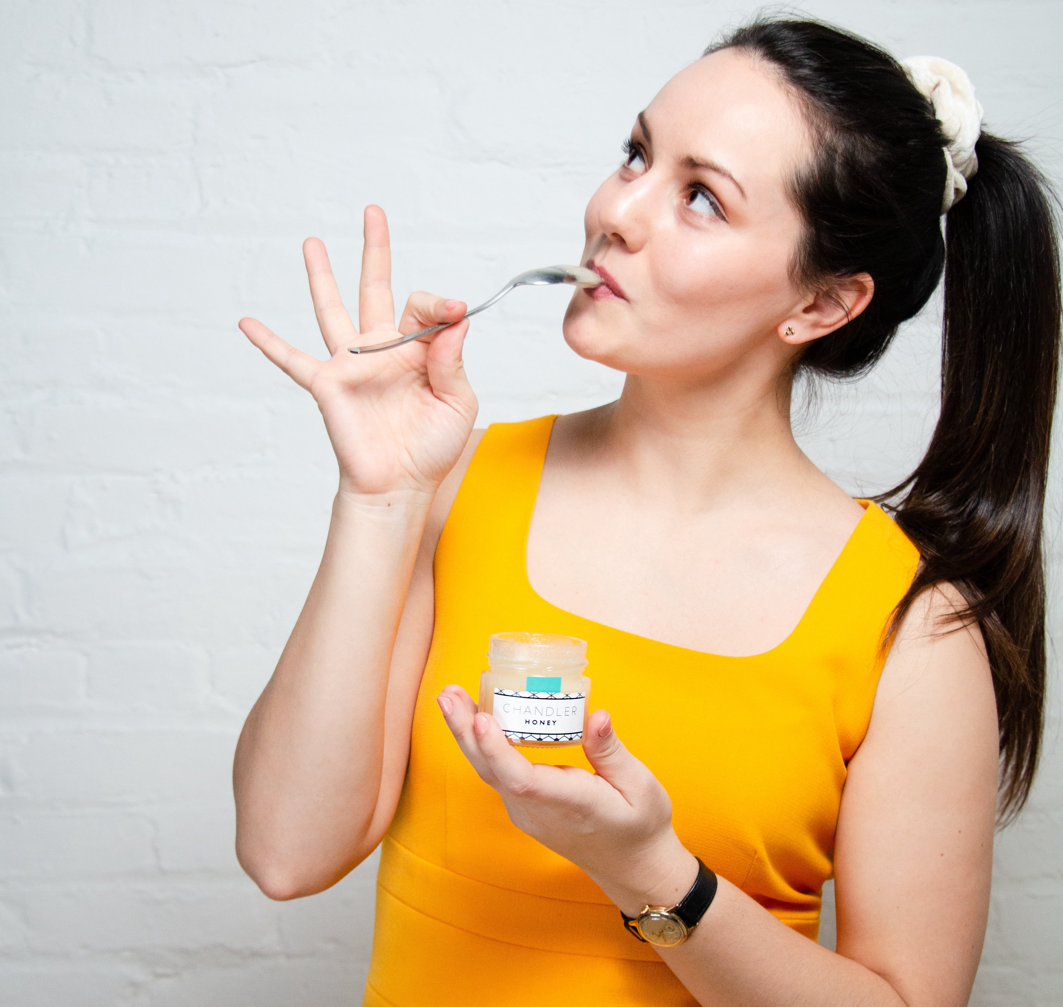 Tique Chandler holds a jar of Chandler Honey while tasting a spoonful of the honey.