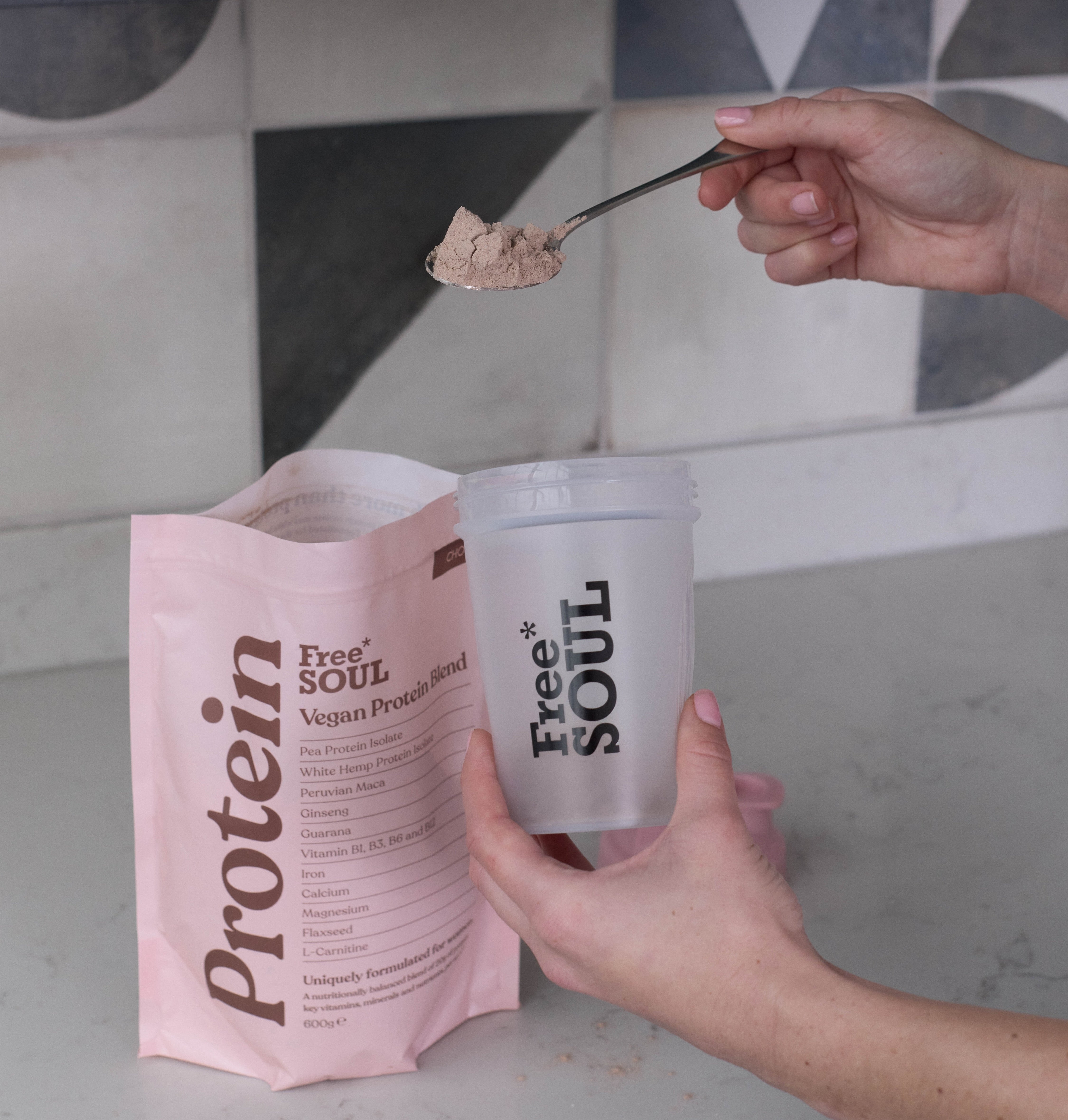 A hand pours a spoonful of Free Soul’s Vegan Protein Blend into a Free Soul cup.
