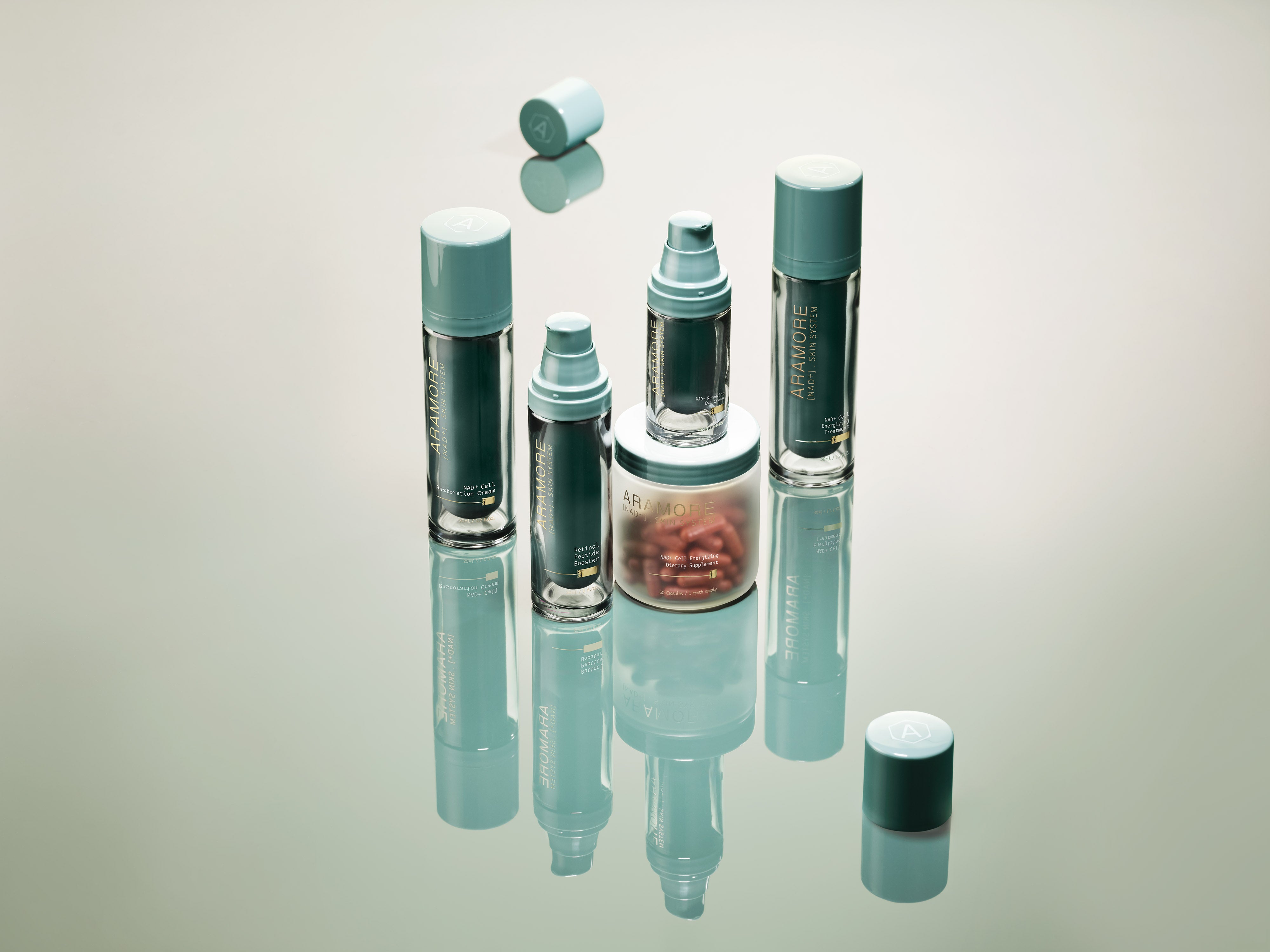 The full Aramore NAD+ Skin System product lineup including topical treatments, a restoration cream, a retinol booster, and dietary supplement capsules, arranged on a reflective surface with caps floating mid-air.